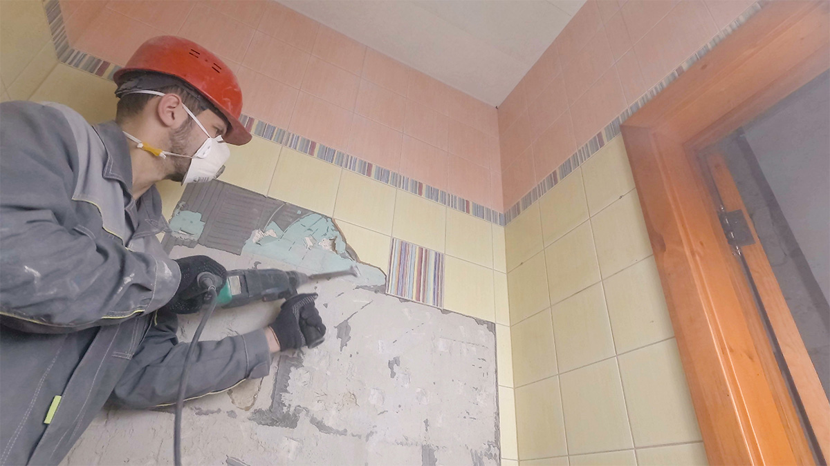 Demolition of old tiles with jackhammer. Renovation of old walls in the bathroom or kitchen.
